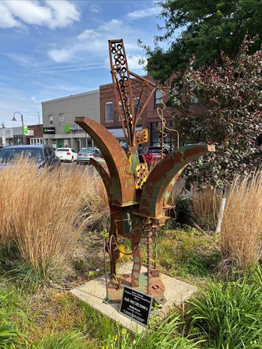 Rusted metal sculpture resembling a plant or stalk. 