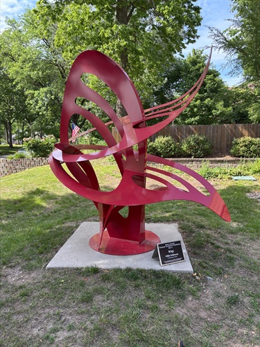 Tall red sculputre designed to look like butterfly wings that intersect each other