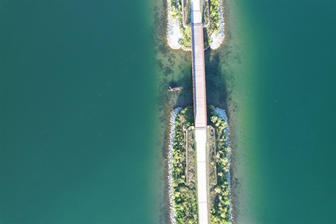 Boat on water crossing under a bridge