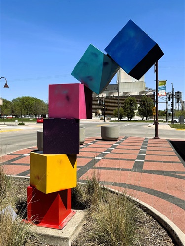 Uniquely colored metal cubes stacked on top of each other appearing like they are tipping over