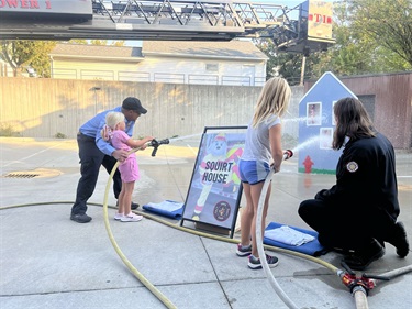 Child in a fire fighter costume posing with Sparky the dog